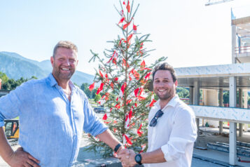 Handschlag vor dem geschmückten Richtbaum, der Standhaftigkeit und Langlebigkeit symbolisiert: Andreas Schwaighofer (Zimmerei Schwaighofer) und Florian Huber (Projektleiter bei Unterberger)